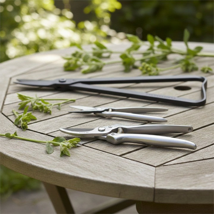 precision pruning shears and garden snips arranged on an outdoor wooden table with fresh cut stems, showcasing essential pruning tools for healthy plant care